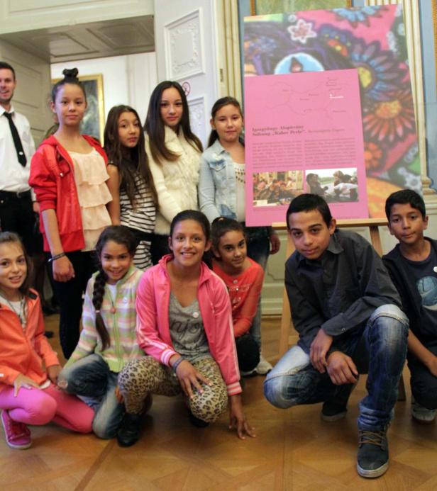 Eine Gruppe von Kindern posiert vor einem farbenfrohen Poster in einem Innenraum.