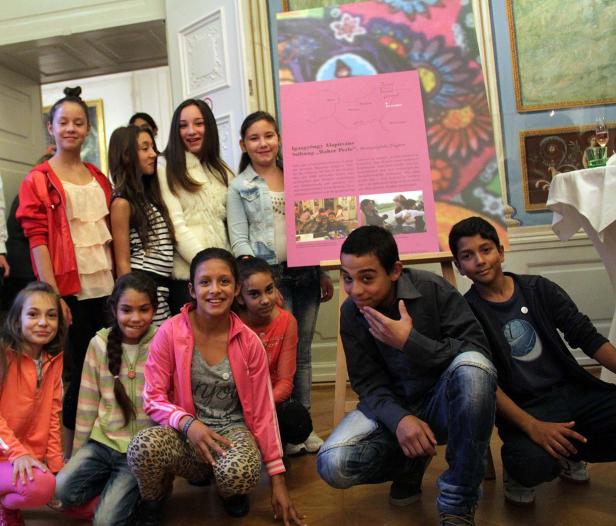 Eine Gruppe von Jugendlichen posiert vor einem Poster in einem Innenraum.