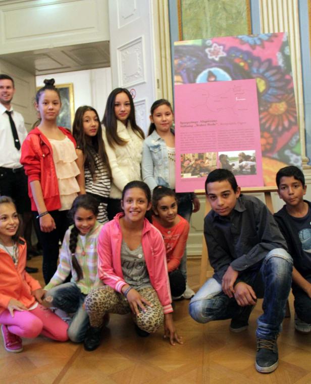 Eine Gruppe von Kindern posiert vor einem Poster in einem Raum.