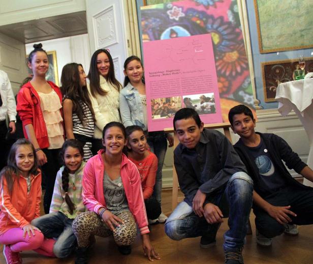 Eine Gruppe von Jungen und Mädchen posiert vor einem farbenfrohen Poster.