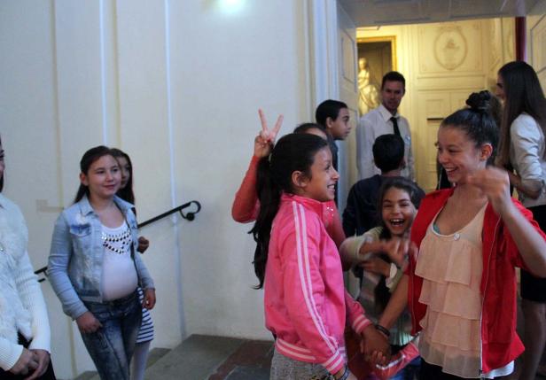 Eine Gruppe lachender Kinder steht in einem hellen Gebäude.