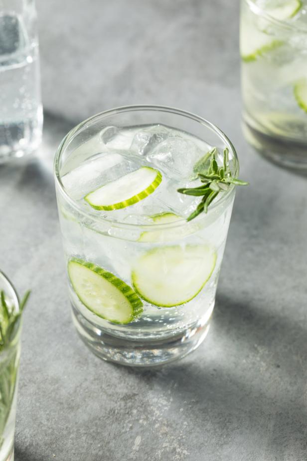 Ein erfrischendes Getränk mit Gurkenscheiben, Eis und Rosmarin in einem Glas.