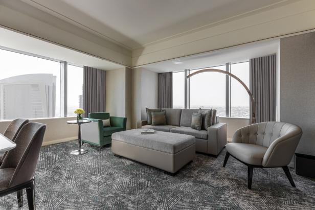 Ein Wohnzimmer mit grauen Möbeln und großen Fenstern mit Ausblick.