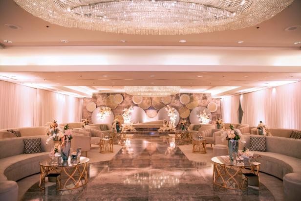 Ein elegant dekorierter Veranstaltungsraum mit Sofas, Tischen und Blumenarrangements.