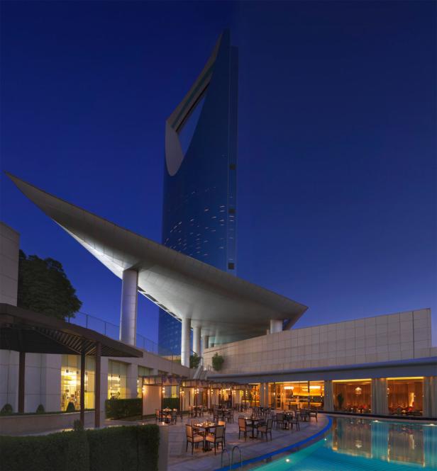 Das Kingdom Centre-Gebäude überblickt einen Außenpool und einen Restaurantbereich bei Nacht.
