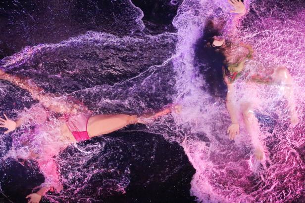 Zwei Personen treiben im violett gefärbten Wasser.