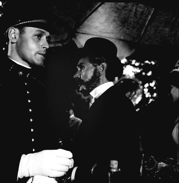 Ein Polizist in Uniform und ein Mann mit Bart und Hut stehen im Gespräch.