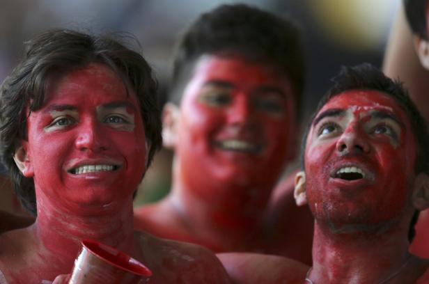 Drei junge Männer haben ihre Gesichter und Körper rot bemalt.