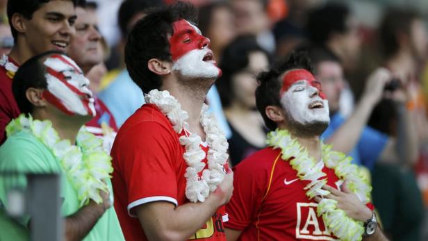 Fußballfans mit Gesichtsbemalung und Blumenketten singen oder jubeln.