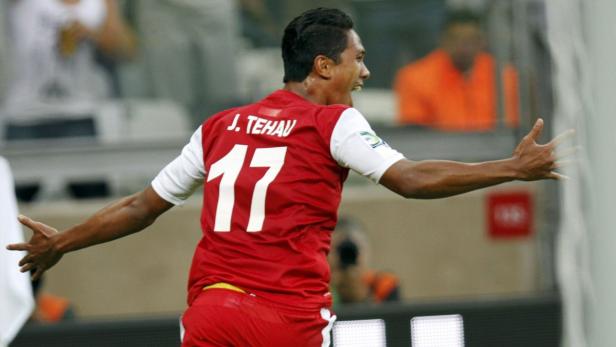 J. Tehau jubelt mit ausgestreckten Armen in seinem roten Fußballtrikot mit der Nummer 17.