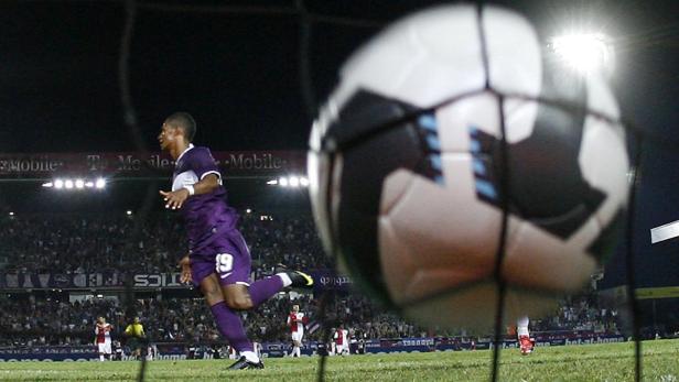 Ein Fußballspieler jubelt vor einer Zuschauermenge, der Ball ist im Netz.