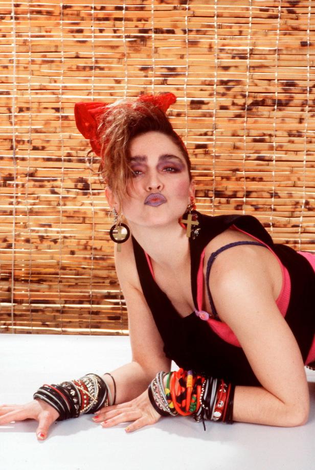 Madonna in den 1980er Jahren mit roter Schleife im Haar und vielen Armbändern.