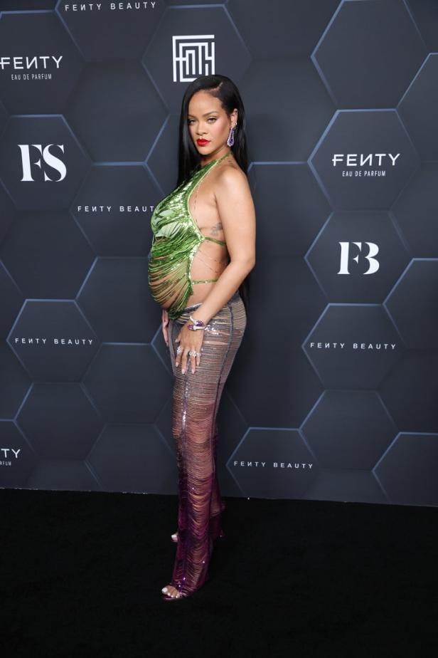 Rihanna posiert in einem grünen Oberteil und einer transparenten Hose auf einem schwarzen Teppich.