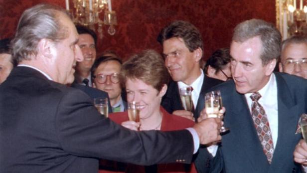 Eine Gruppe von Menschen stösst mit Sektgläsern an.