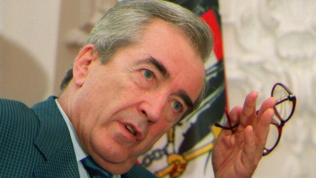 Ein Mann mittleren Alters hält eine Brille in der Hand.