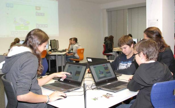 Schüler arbeiten mit Laptops an einem Projekt im Klassenzimmer.