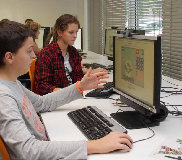 Schüler arbeiten an Computern in einem hellen Raum.
