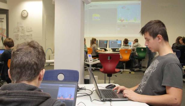 Schüler arbeiten in einem Computerraum an ihren Laptops.