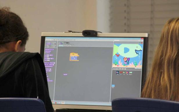 Ein Kind programmiert ein Unterwasserspiel mit Fischen auf einem Computer.