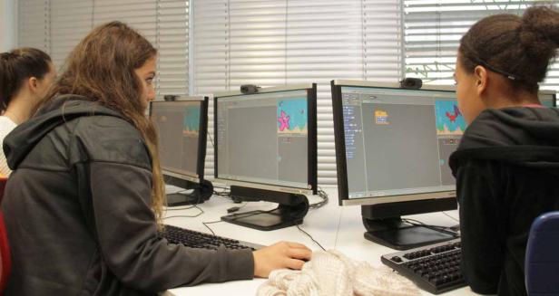 Schülerinnen arbeiten an Computern mit einer grafischen Programmieroberfläche.