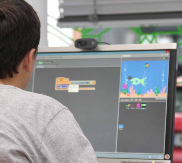 Ein Kind programmiert ein Spiel mit Fischen auf einem Computer.