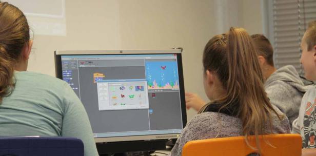 Schüler arbeiten an einem Computer mit einer Scratch-Programmieroberfläche.