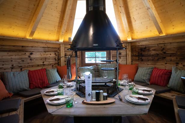 Einrichtung mit Grillplatz und Sitzgelegenheiten in einem Holzhaus.