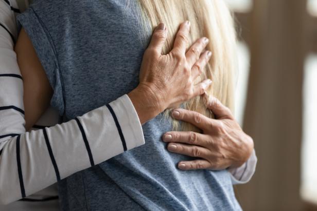 Eine Person umarmt eine andere Person mit blonden Haaren.