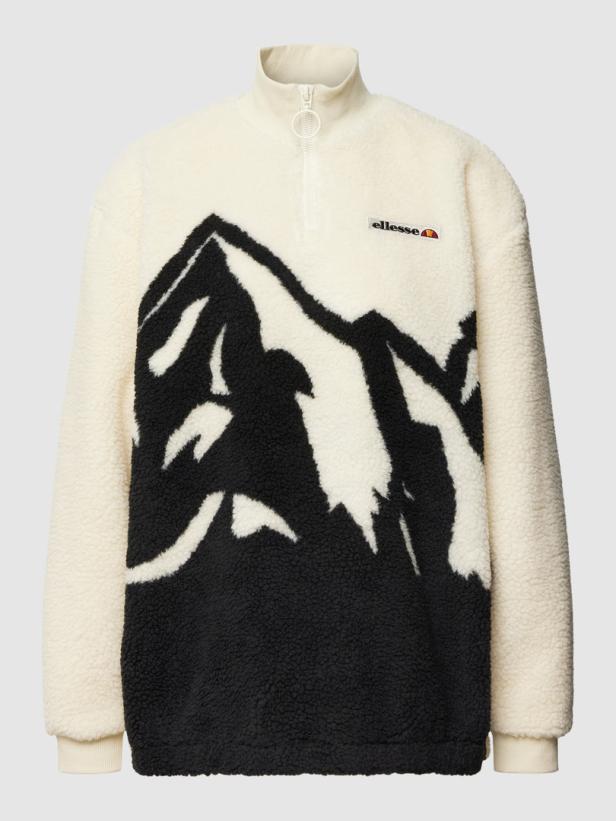 Ein cremefarbener Ellesse-Fleece-Pullover mit einem schwarzen Bergmotiv.