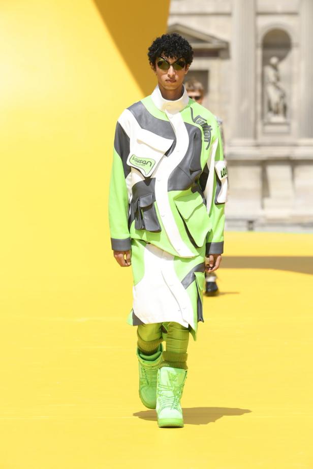 Ein Model auf dem Laufsteg in einem grün-weiß-grauen Louis Vuitton Outfit.
