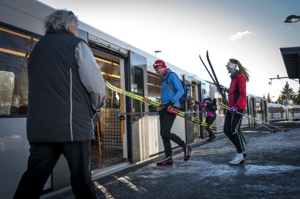 Skifahrer steigen mit ihren Skiern in einen Zug ein.