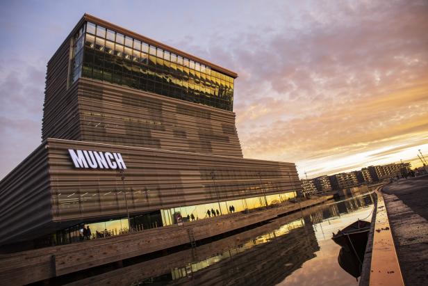 Das Munch Museum in Oslo bei Sonnenuntergang, mit Spiegelungen im Wasser.