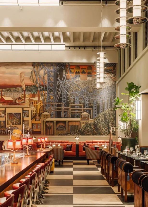 Innenansicht eines eleganten Restaurants mit einer großen Wandmalerei im Hintergrund.