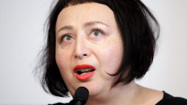 Eine Frau mit roten Lippen spricht in ein Mikrofon.