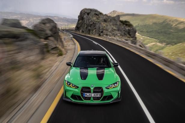 Ein grüner BMW M3 fährt auf einer kurvenreichen Bergstraße.