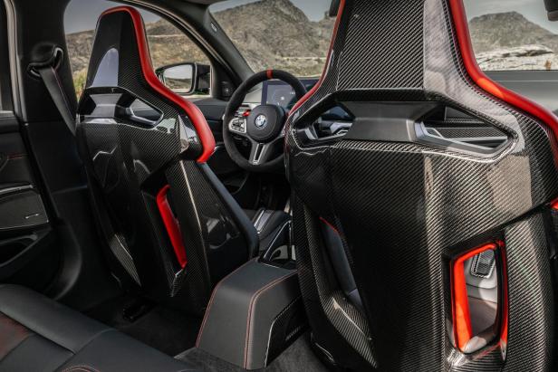 Das Interieur eines BMW M3 mit Carbon-Schalensitzen und roten Akzenten.