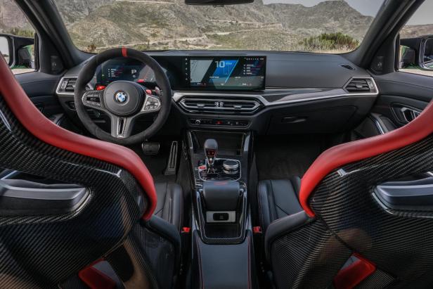 Innenansicht eines BMW M3 mit roten Carbon-Sportsitzen und Blick auf die Berglandschaft.