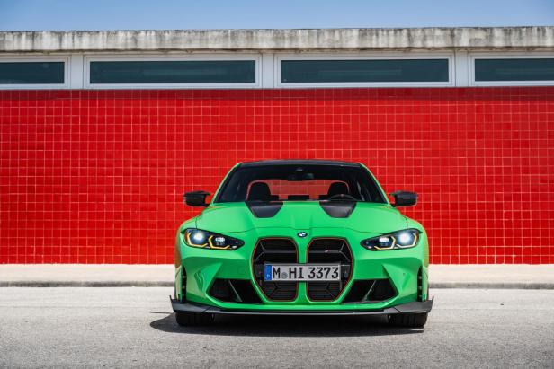 Ein grüner BMW M3 steht vor einer roten Wand.