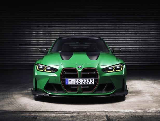 Ein grüner BMW M3 steht vor einem Rolltor.