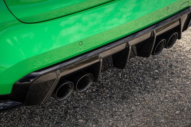 Die Heckpartie eines grünen BMW M3 mit vier Auspuffrohren und Carbon-Diffusor.