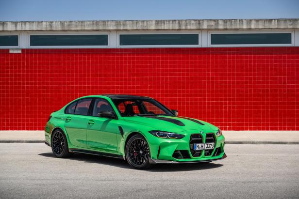 Ein grüner BMW M3 steht vor einer roten Kachelwand.
