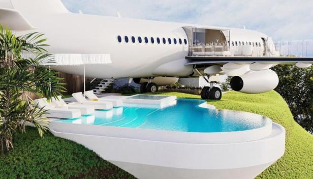 Ein umgebautes Flugzeug dient als luxuriöse Villa mit Pool und Liegestühlen.