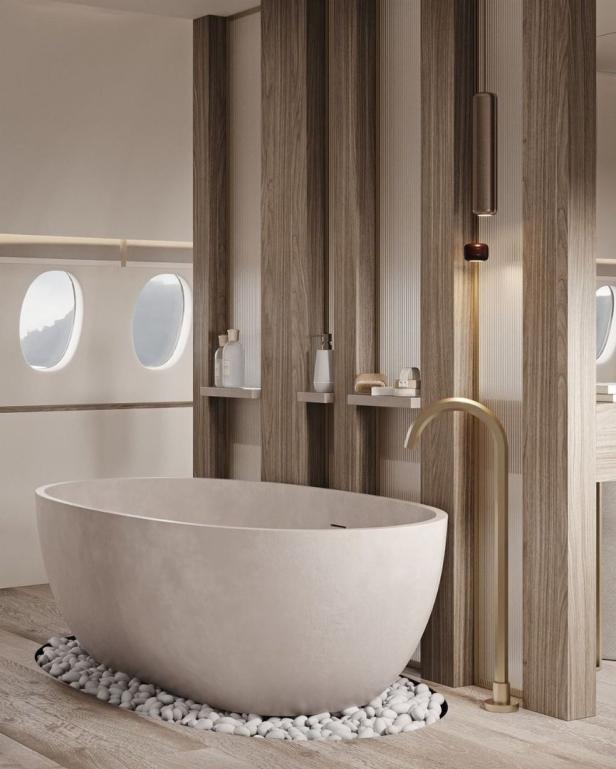 Ein modernes Badezimmer mit einer freistehenden Badewanne auf weißen Kieselsteinen.
