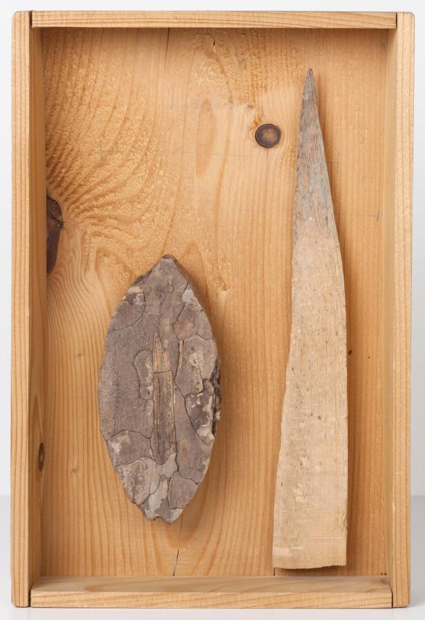 Ein Holzrahmen enthält ein Blatt und ein Holzstück.