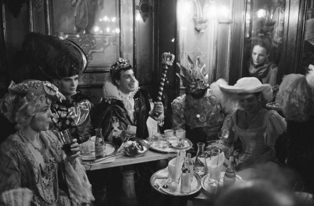 Eine Gruppe von Menschen in historischen Kostümen sitzt an Tischen in einem Restaurant.
