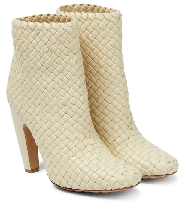 Ein Paar cremefarbene, gewebte Lederstiefeletten mit Absatz stehen nebeneinander.
