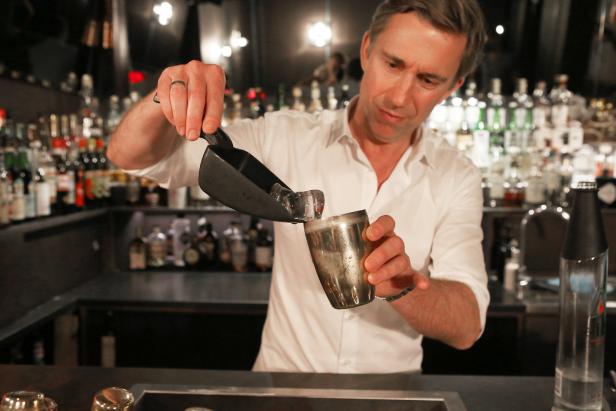 Ein Barkeeper füllt Eiswürfel in einen Cocktail Shaker.