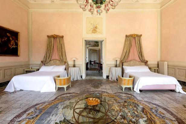 Ein prächtiges Schlafzimmer mit zwei Betten, einem bemalten Boden und einem Kristalllüster.