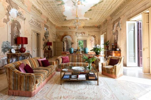 Ein reich verziertes Wohnzimmer mit Fresken an Wänden und Decke, eingerichtet mit antiken Möbeln.
