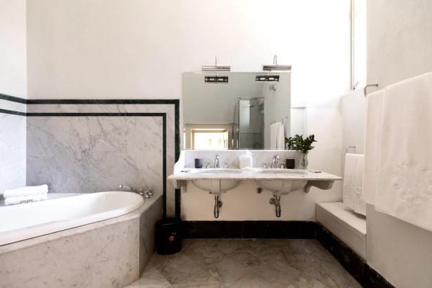 Ein Badezimmer mit Marmorverkleidung, einer Badewanne und einem Doppelwaschbecken.